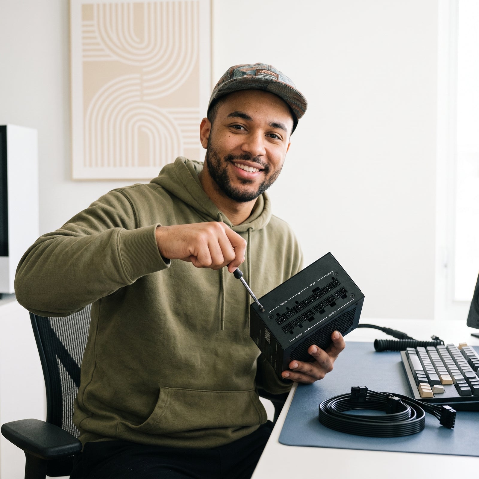 A gamer, mid-twenties, casually interacting with a 1000W fully modular ATX PC power supply in a modern gaming setup with subt