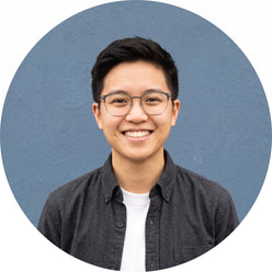 A circular portrait of a smiling young person with short, dark hair and glasses, representing Tech Curated.