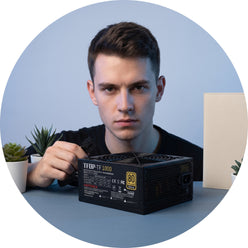 Circular portrait of a young man, @pure_pc, with a focused expression, subtly interacting with a 1000W PC power supply.